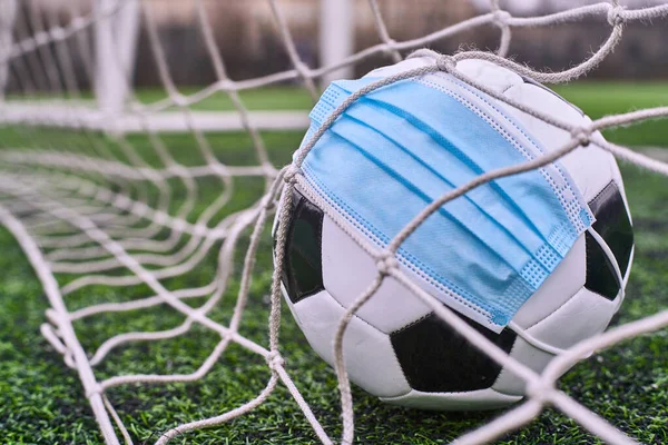 Futbol topu tıbbi maskeli Gol Ağı 'nda. Boş Stadyum. Futbol Yarışmalarının İptal Edilmesi