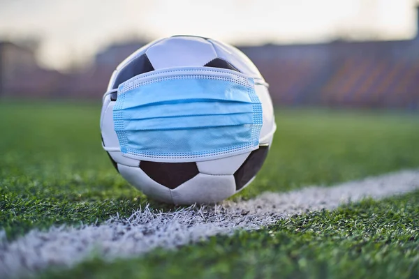  Siyah ve Beyaz Futbol Balosu Stadyumun Boş Koltukları 'nın Arkasında Tıbbi Maske Altında. Karantina zamanında futbol müsabakaları. COVID-19 Konsepti