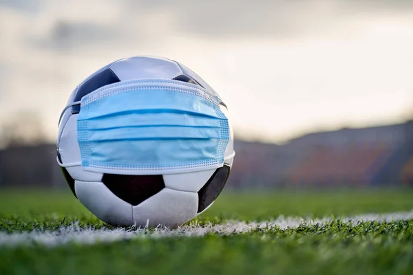  Siyah ve Beyaz Futbol Balosu Stadyumun Boş Koltukları 'nın Arkasında Tıbbi Maske Altında. Karantina zamanında futbol müsabakaları. COVID-19 Konsepti
