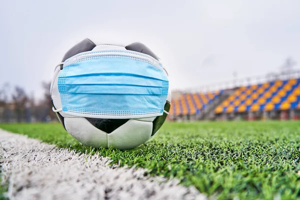  Siyah ve Beyaz Futbol Balosu Stadyumun Boş Koltukları 'nın Arkasında Tıbbi Maske Altında. Karantina zamanında futbol müsabakaları. COVID-19 Konsepti