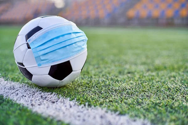  Siyah ve Beyaz Futbol Balosu Stadyumun Boş Koltukları 'nın Arkasında Tıbbi Maske Altında. Karantina zamanında futbol müsabakaları. COVID-19 Konsepti