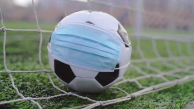 Futbol topu tıbbi maskeli Gol Ağı 'nda. Boş Stadyum. Futbol Yarışmalarının İptal Edilmesi