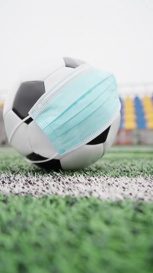 空荡荡的体育场里的足球 戴着医用面罩的足球球 以保护自己不受感染 在没有人的塑料座椅的背景下 垂直录像 — 图库视频影像