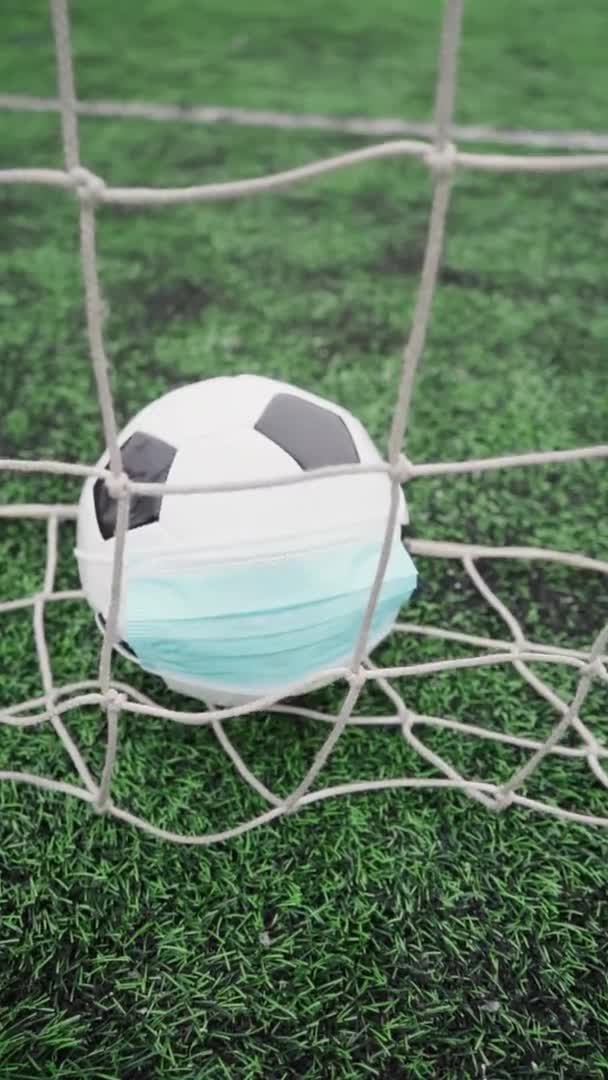 球技場草の上に医療マスクを着用サッカーボール サッカーのゴールネットで黒と白のボール 垂直ビデオ — ストック動画