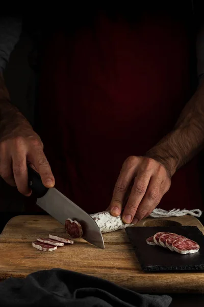 Cutting salchichon, dark food style, vertical