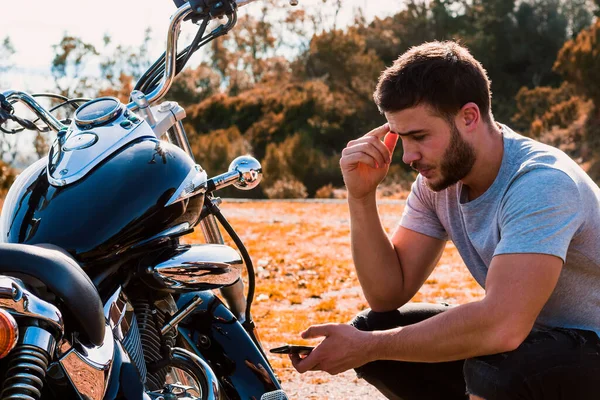 Motosiklet arızası yüzünden çömelmiş bir motorcu.