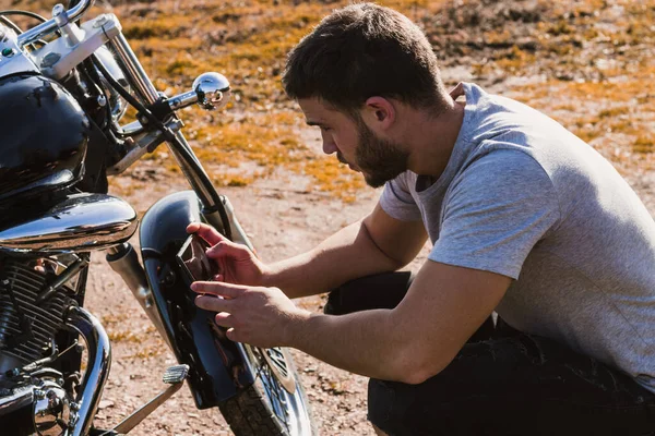 Motosikletli, motorsikletinin bozulmasının fotoğrafını çekiyor.