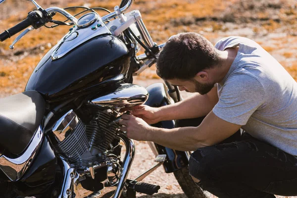 Motosiklet arızası yüzünden çömelmiş bir motorcu.
