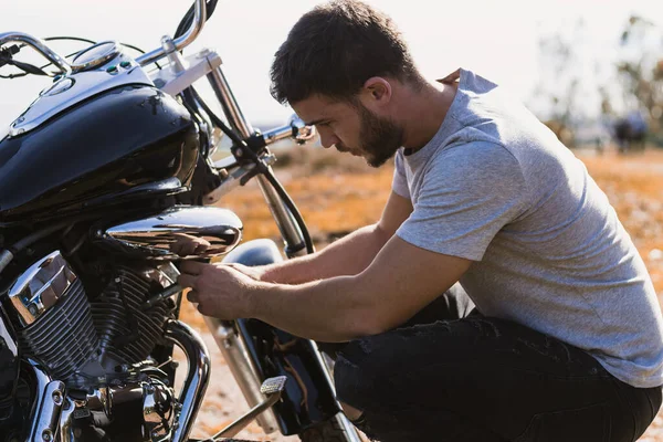 Crouching biker worried about a motorcycle breakdown