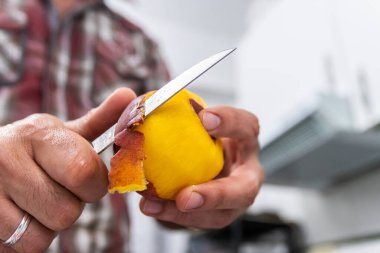 Bıçakla şeftali soyan adam yakından görülüyor.