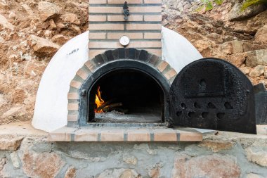 Beyaz boyalı sanatkar ahşap fırın. Kapı açık ve ateş içinde.