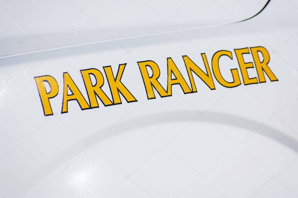 Park Ranger text sign on the side of white service vehicle. Close up.