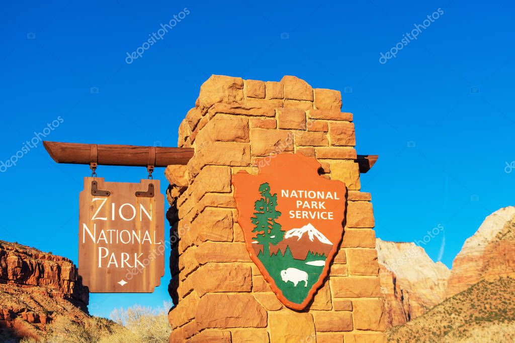 Zion National Park entrance sign with National Park Service arrowhead insignia on a beautiful sunny winter day with blue sky - Zion National Park, Utah, USA - 2020