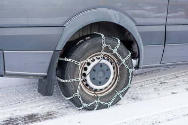Minibüsün arka tekerleğinde kar zincirleri var. Yol üzerinde taze kış karı var. - Moab, Utah, ABD - 2020