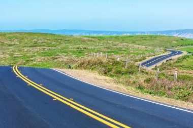 Açık güneşli bir günde Kaliforniya, Point Reyes Ulusal Deniz Kıyısı 'nda Pasifik Okyanusu sahili manzaralı iki şeritli yolda ilerliyoruz.