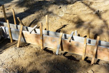 Ahşap işlemeli beton kaldırım inşaatı. Kazılmış bölge. Tahta, tahta kazıkları yere çakılarak dik konuma getirilir..