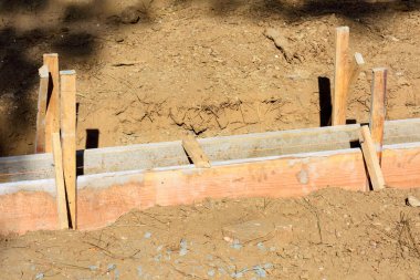 Ahşap işlemeli beton kaldırım inşaatı. Kazılmış bölge. Tahta, tahta kazıkları yere çakılarak dik konuma getirilir..