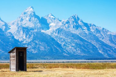 Antilop Düzlükleri Vadisi 'ndeki Mormon Row Tarihi Bölgesi' nde terk edilmiş ahşap bir ek bina. Grand Teton Ulusal Parkı 'ndaki Teton Dağı' nın arka plandaki görkemli zirveleri