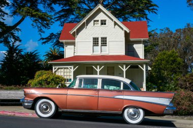 Classic 1957 Chevrolet Bel Air four door sedan parked on on the street in front of eclectic Queen Anne architecture style historic building - San Francisco, California, USA - 2021 clipart