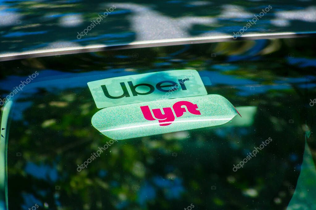 Lyft and Uber logo on stickers attached to rear car window advertise a vehicle offering shared rides in Silicon Valley - San Francisco, California, USA - 2021