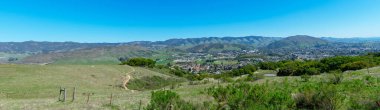 Güneşli bahar gününde Piskopos Tepesi Yolu 'ndan San Luis Obispo kentsel alanının yüksek panoramik manzarası ve Santa Lucia Dağları.