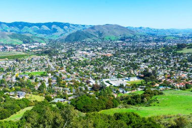 San Luis Obispo kentsel alanının manzarası yükseliyor ve güneşli bahar gününde Bishop Tepesi 'nden Santa Lucia Dağları' nın yeşil dağları.