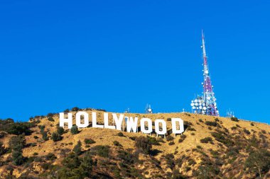 Hollywood işareti beyaz harfler ve iletişim kulesi antenleri mavi gökyüzünün altında, Mount Lee 'de. - Los Angeles, Kaliforniya, ABD - 2020