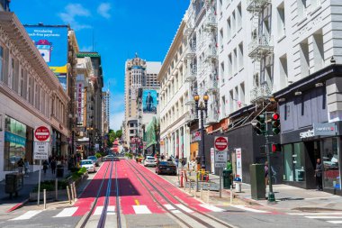 Güneşli bir günde Ellis Caddesi kavşağından yokuş yukarı giden kırmızı Powell Caddesi 'ndeki boş bir teleferik demiryolu manzarası. - San Francisco, Kaliforniya, ABD - Temmuz, 2021