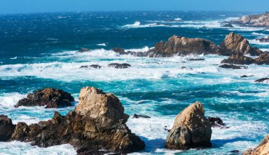 Okyanus dalgaları Garrapata Eyalet Parkı 'ndaki Big Sur California sahilinin engebeli kıyı şeridine çarpar..