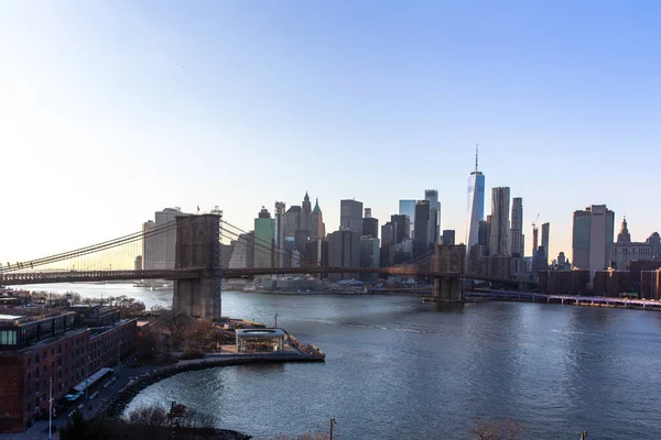 夕日に高層ビルが並ぶニューヨーク市のスカイライン マンハッタン ブルックリン間の接続としてのブルックリン橋 — ストック写真