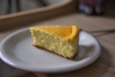 Beyaz bir tabakta çatallı New York peynirli kek dilimi. Alan derinliği