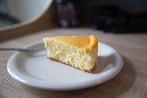 フォークのついた白い皿の上のニューヨークチーズケーキの一部だ 場の深さ — ストック写真