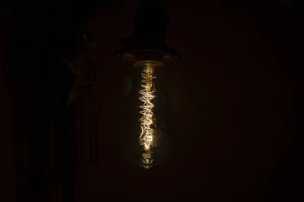 Incandescent bulb. Vintage hanging Edison light bulb over black background