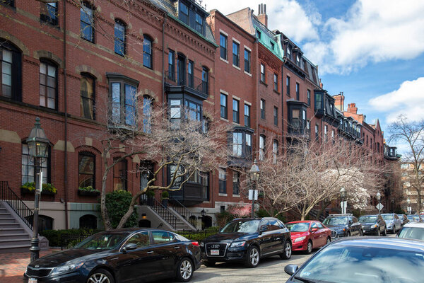 Boston, MA - April 8 2021: Rows of brownstone apartment brick buildings in Boston with front yards, trees and in Pennsylvania