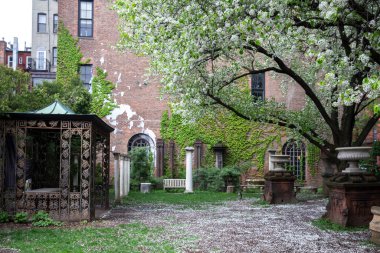 New York City - 18 Nisan 2021: Nolita, Manhattan 'daki Elizabeth Street Garden' da sarmaşık sütunları ve figürlerle kaplı kırmızı tuğla bina.