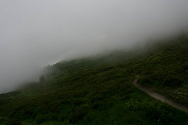 Alpler 'in manzara manzarası. Fırtınalı hava nedeniyle tepeler bulutlar ve sisle kaplıdır. Kasvetli görünüm