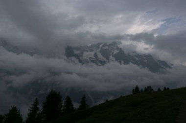 Alpler 'in manzara manzarası. Fırtınalı hava nedeniyle tepeler bulutlar ve sisle kaplıdır.