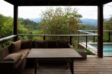 iki hasır sandalyeli balkon ya da teras ve dağlık bir manzaraya bakan saksı bitkisi..