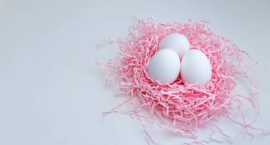 Pastel Paskalya kompozisyonu, pembe arka planda dekoratif bir yuvadaki yumurtalar.,