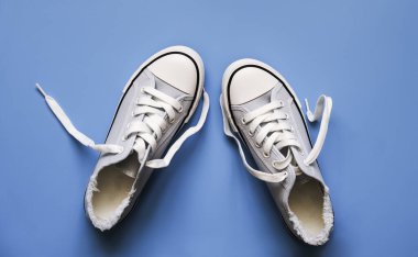 Mavi arka planda beyaz bağcıklı mavi spor ayakkabılar.