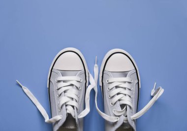 Mavi arka planda beyaz bağcıklı mavi spor ayakkabılar.