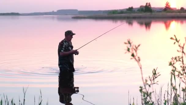 Silhuett av en fiskare, en man som fiskar i floden vid solnedgången. — Stockvideo