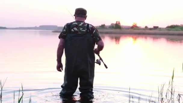 Un pescatore entra in acqua con una speciale tuta impermeabile, — Video Stock