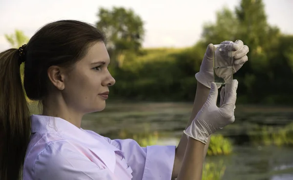 Flicka laboratorieassistent tar vattenprover i sjön, begreppet ekologi — Stockfoto