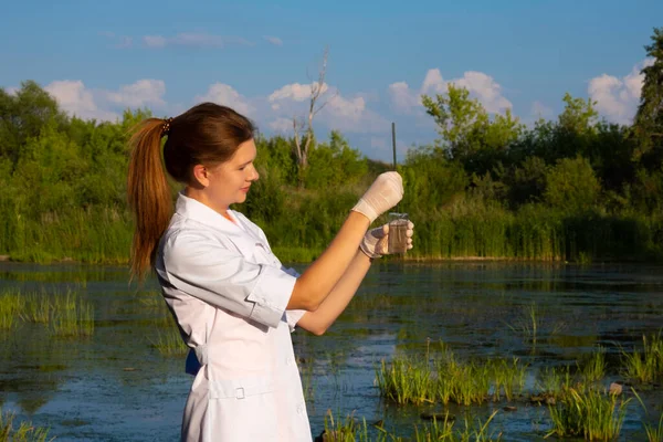 Girl laboratory assistant takes water samples in the lake, the concept of ecology — Stock Photo, Image
