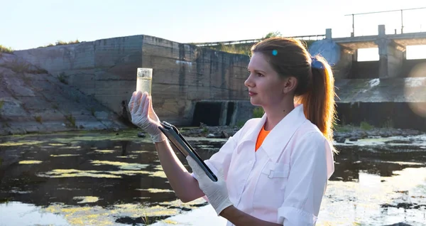 En kvinnlig ekolog tar vattenprover för förorening, begreppet ekologi. — Stockfoto