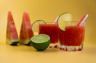 İki bardak karpuz kokteyli ve sarı arka planda bir dilim karpuz ve limon. Yüksek kalite fotoğraf