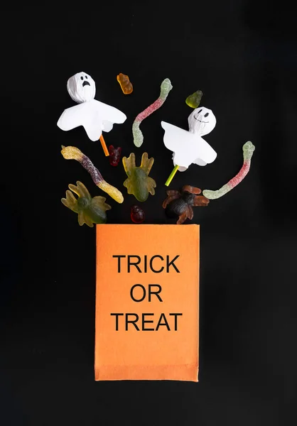 Orangefarbene Tüte mit Süßigkeiten für die Halloween-Feier. die Beschriftung auf der Packung Trick oder behandeln — Stockfoto