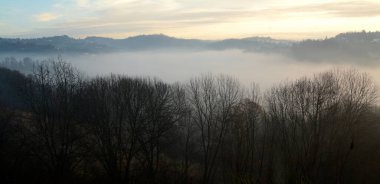 Sonbahar sisleri tepeler ve ağaçlar arasında bir vadiyi sarıyor.