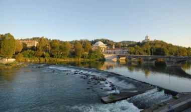 Torino 'daki Po nehri Murazzi tarafından fotoğraflandı. Nehirde yüzen kanocular Monte dei Capuccini 'nin üzerinde durduğu tepenin altında yelken açarlar..